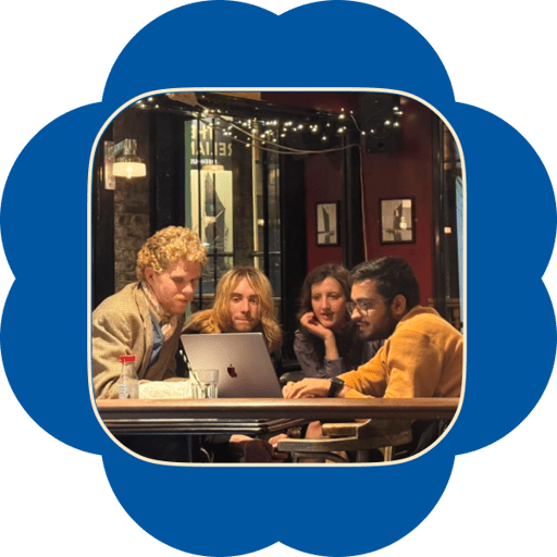 Four people gathered around a laptop at a candlelit pub table, building together